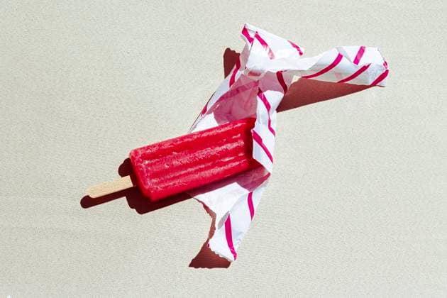 Red popsicle partially unwrapped on a sunny day, RDTF00434