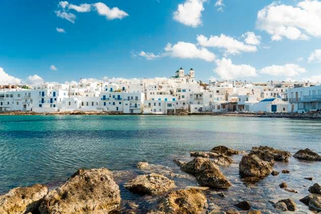 Scenic view of the traditional white houses in Naousa, Paros with a rocky shoreline and blue sky., TAMF04775