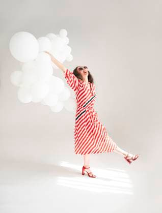 Creative Highlights Symbolbilder Middle aged woman in a retro striped dress holding cloud-shaped balloons in a studio model released, Symbolfoto, VRAF01156