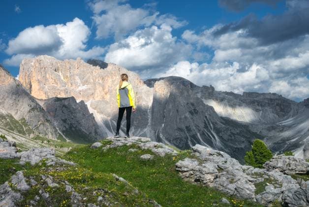 Girl on the hill with yellow flowers and green grass in beautiful alpine mountain valley at sunset in summer. Landscape with young woman in alps, sky with clouds, rocks. Travel in Dolomites, Italy Model Released DenisBilytskyi_ID26964_778295_016 Copyright: xDenisxBilytskyix