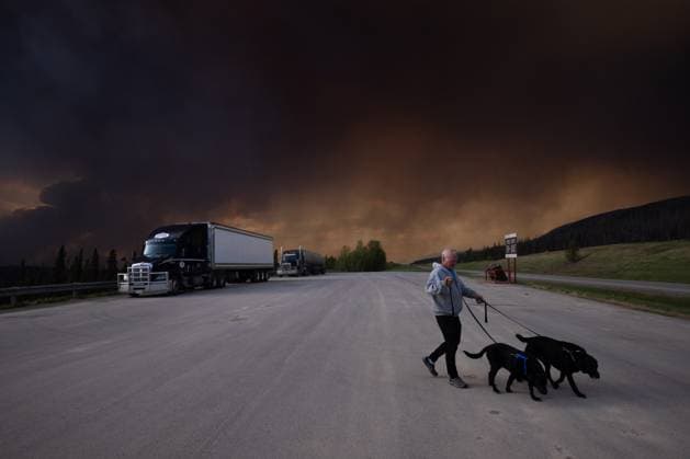 May 30, 2025, Buckinghorse River, Bc, Canada: A tourist takes his dogs out for a quick break under billowing wildfire smoke off Highway 97 north of Buckinghorse River, B.C. on Friday, May 30, 2025. Buckinghorse River Canada  - ZUMAc35_ 20250530_zaf_c35_189 Copyright: xNasunaxStuart-Ulinx