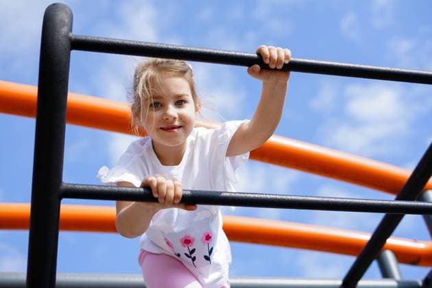 Creative Highlights Symbolfotos Smiling girl climbing bars at playground under blue sky Limanowa, Lesser Poland Voivodeship, Poland R_ZRPS250521-1734385-01 ,model released, Symbolfoto