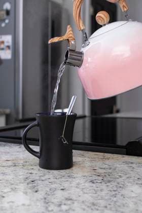 Pouring hot water from pink kettle into black mug with teabag Carlisle, Pennsylvania, United States R_RAFB25061240-1767912-01