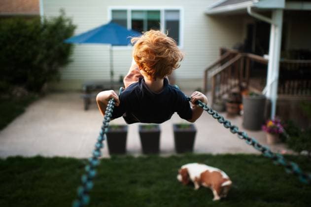 Creative Highlights Symbolbilder Young boy swinging high in backyard with dog in grass Grimes, Iowa, United States CR_LIPF25061682-1762181-01 ,model released, Symbolfoto