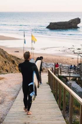 Surfer walking on wooden boardwalk carrying surfboard in sagres, Portugal, Faro District, Sagres CR_MGUJ250617-1769959-01 ,model released, Symbolfoto