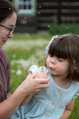Creative Highlights Symbolbilder Mom holds puffball while daughter blows and seeds rise up Kelowna, British Columbia, Canada R_PESF250616F-1766531-01 ,model released, Symbolfoto