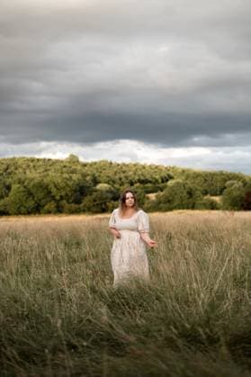 Creative Highlights Symbolbilder Woman walking in tall grass before the storm Corby, England, United Kingdom R_JNDO2506161C-1754946-01 ,model released, Symbolfoto