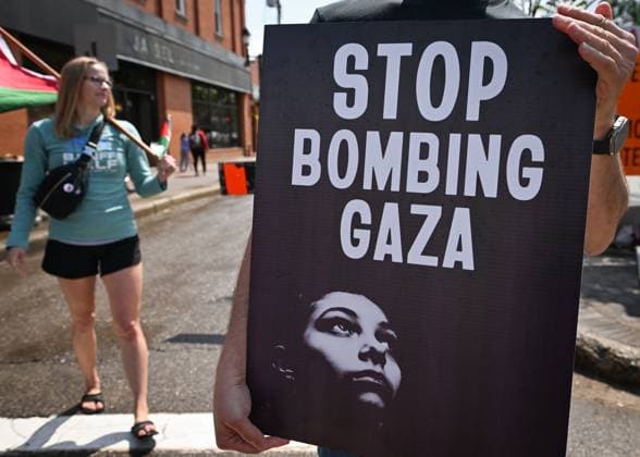 Woman With Israeli Flag Attacked During Edmonton Pro-Palestine Protest EDMONTON, CANADA JUNE 22: A protester holds a placard with words Stop Bombing Gaza as members of the local Palestinian diaspora, joined by Iranian and other Middle Eastern Muslim protesters, along with local activists, gather on White Avenue in Edmonton for the Hands Off Palestine, Iran, Syria, Yemen, Lebanon protest on June 22, 2025, in Edmonton, Alberta, Canada. Edmonton Canada Copyright: xArturxWidakx originalFilename: widak-womanwit250622_npk7X.jpg