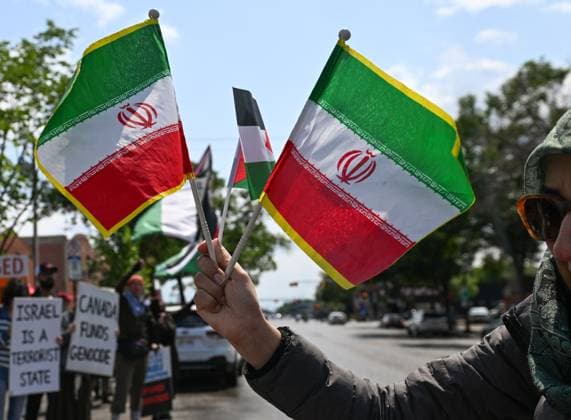 Woman With Israeli Flag Attacked During Edmonton Pro-Palestine Protest EDMONTON, CANADA JUNE 22: A protester holds Iranian flags as members of the local Palestinian diaspora, joined by Iranian and other Middle Eastern Muslim protesters, along with local activists, gather on White Avenue in Edmonton for the Hands Off Palestine, Iran, Syria, Yemen, Lebanon protest on June 22, 2025, in Edmonton, Alberta, Canada. Edmonton Canada Copyright: xArturxWidakx originalFilename: widak-womanwit250622_npPHJ.jpg