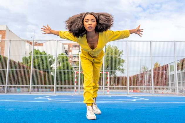 Creative Highlights Symbolbilder Confident young woman with arms outstretched dancing on basketball court model released, Symbolfoto, DLTSF03414