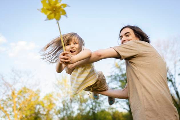 Creative Highlights Symbolbilder Father lifting daughter with a pinwheel outdoors in Warsaw model released, Symbolfoto, ASVF00295
