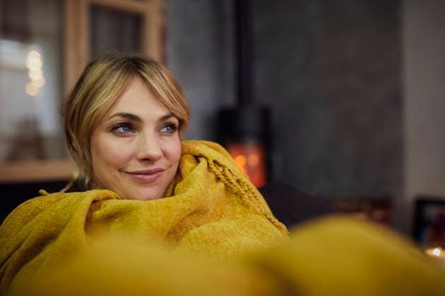 Creative Highlights Symbolbilder Woman relaxing at home wrapped in a cozy blanket by the fireplace model released, Symbolfoto property released, RBF09956