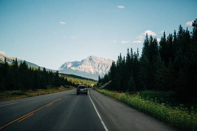 Car drives by forest highway with Canadian Rocky mountains Jasper, Alberta, Canada R_XPQF250623C-1735360-01