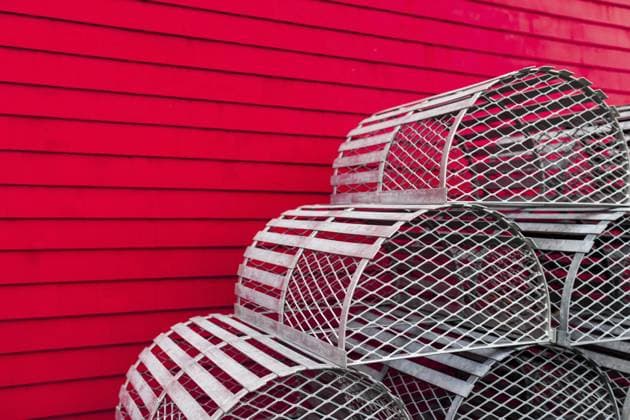Wiederholung von Metallnachbildungen von Hummerfallen, die vor einer kräftigen roten Wand gestapelt sind und ein geometrisches Industriedesign in Lunenburg, Nova Scotia, Kanada, Nordamerika, bilden, Nordamerika Repetition of metal recreations of lobster traps stacked in front of a bold red wall, creating a geometric industrial design in Lunenburg, Nova Scotia, Canada, North America Copyright: imageBROKER MarkxSpowart iblmsp14204813.jpg