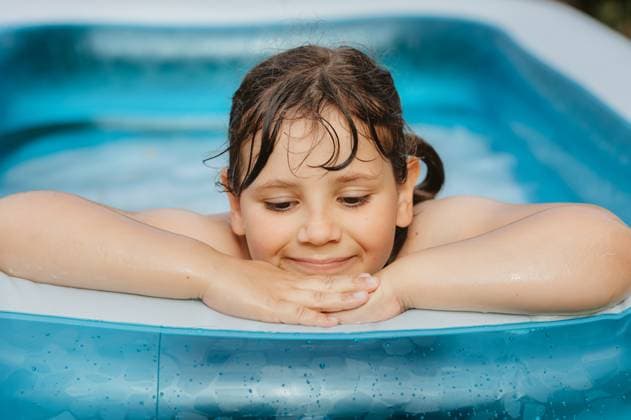 Creative Highlights Symbolbilder Smiling child girl with wet hair resting on the inflatable pool edge. Corby, England, United Kingdom R_JNDO250703C-1775649-01 ,model released, Symbolfoto