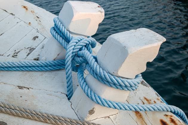 Mit einem nautischen Knoten gebundene Festmacher Close-up of blue mooring ropes tied in a nautical knot around white wooden bollards on a vintage boat (License=RF) Copyright: xZoonar.com AleksandarxVarbenovx 23717097