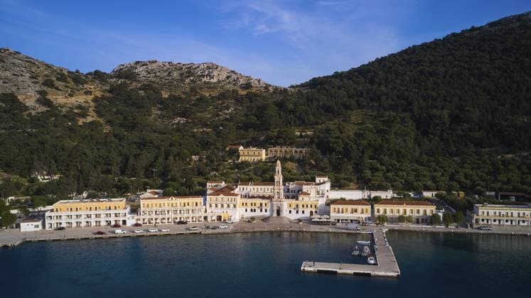 Drohnenaufnahme, Küstenlinie mit Hafen und historischen Gebäuden umgeben von Bergen, Karwoche, Bucht von Panormitis, Kloster Panormitis, Symi, Dodekanes, Griechische Inseln, Griechenland, Europa Drone shot, coastline with harbour and historic buildings surrounded by mountains, Holy Week, Bay of Panormitis, Panormitis Monastery, Symi, Dodecanese, Greek Islands, Greece, Europe Copyright: imageBROKER RalfxAdler ibxraa13846923.jpg