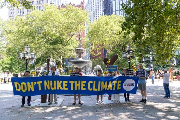 July 16, 2025, New York, New York, USA: Members of New York Campaign To Abolish Nuclear Weapons (NYCAN) hold sunflowers and a banner and signs that read DON T NUKE THE CLIMATE NUCLEAR DISARMAMENT NOW! NUCLEAR WEAPONS KILL EVERYTHING FIRST WE BOMBED NEW MEXICO at a vigil in City Hall Park marking 80 years since the U.S. government s Trinity Test, the detonation of the first nuclear weapon on July 16, 1945 in the Tularosa Basin in New Mexico. The protest is held across the street from the original Manhattan Project offices at 270 Broadway in lower Manhattan. Demonstrators call for worldwide nuclear abolition and mourn for the illness and harm to people and lands from radioactive contamination caused by nuclear tests and atomic bombs. - ZUMAr174 20250716_znp_r174_015 Copyright: xGinaxMxRandazzox