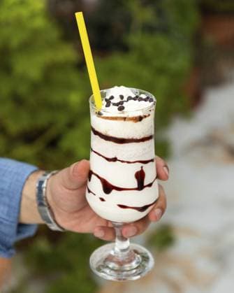 IMAGO Creative, Food, Trend, Iced Coffee Der Barista hält einen erfrischenden Eiskaffee Milchshake mit Schlagsahne, Schokoladensirup und Schokoladenstückchen in der Hand Barista holding a refreshing iced coffee milkshake topped with whipped cream, chocolate syrup, and chocolate chips Copyright: imageBROKER Dr.xMartinxBaumgärtn ibxiqx14302647.jpg