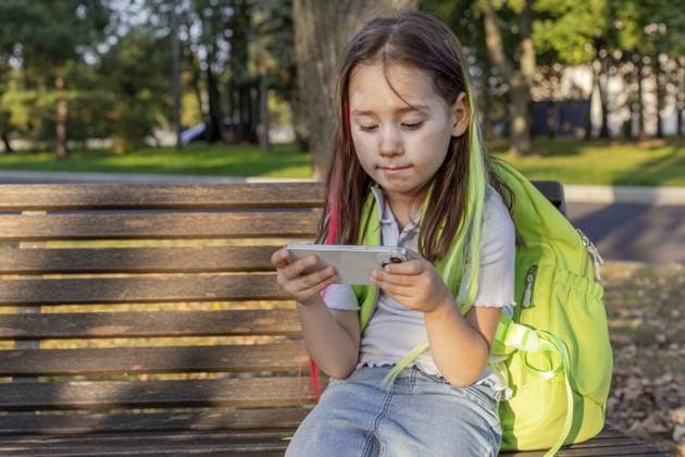 Junges Mädchen entspannt sich auf einer Parkbank und beschäftigt sich mit ihrem Smartphone an einem sonnigen Tag im Freien Young girl relaxing on park bench engaged with smartphone outdoors on a sunny day Copyright: imageBROKER NatashaxZakharova ibxiqx14295550.jpg ,model released, Symbolfoto ,property released