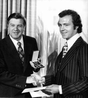 Rugby Fußball Sept. 09, 1976 - Fußball-Spieler Franz Beckenbauer wurde mit dem Bundesverdienstkreuz ausgezeichnet.: Franz Beckenbauer (31), der berühmte bayerische Fußballspieler, hat am 16. September 1976 das Bundesverdienstkreuz am Bande erhalten. Der Kapitän des Fußballvereins Bayern München sowie der westdeutschen Nationalmannschaft, die seit 1974 Weltmeister ist, wurde auf Empfehlung des bayerischen Ministerpräsidenten vom Bundespräsidenten mit dem Verdienstkreuz ausgezeichnet. Das Foto zeigt Franz Beckenbauer (r) nach der Verleihung des Verdienstkreuzes durch den bayerischen Kultusminister Hans Maier (l.). *** Rugby Football Sept 09, 1976 Football Player Franz Beckenbauer was with the Federal Cross of Merit excellent Franz Be  Copyright: xUnitedxArchivesx xkpaxKeystonex 19760909_baf_k09_117 !ACHTUNG AUFNAHMEDATUM GESCHÄTZT!