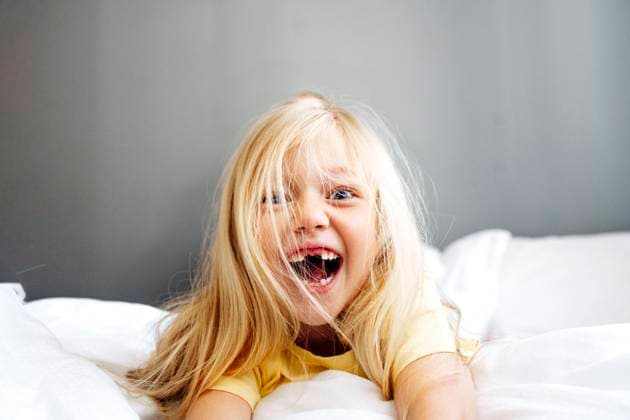 Creative Highlight Symbolbilder Smiling child with blonde hair on bed showing playful emotion model released, Symbolfoto property released, NSTF00531