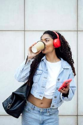 Creative Highlight Symbolbilder Businesswoman listening to music on headphones with coffee in city model released, Symbolfoto, PGF02082