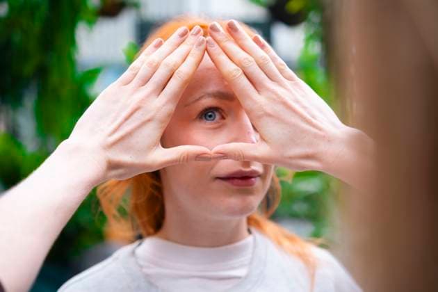 Creative Highlight Symbolbilder Woman gazing through hands forming triangle outdoors model released, Symbolfoto property released, AMWF03597