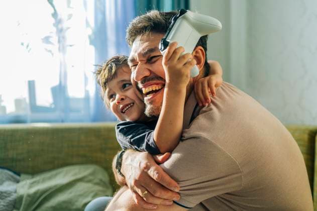 IMAGO Creative, Lifestyle, Gaming Smiling father and child playing console game together at home model released, Symbolfoto property released, ANAF04839