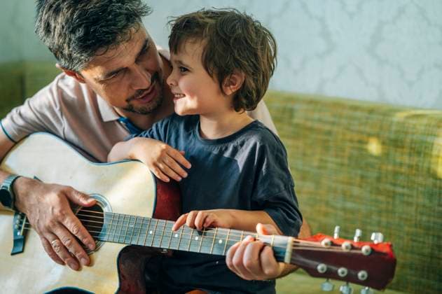 Father teaching son to play guitar at home in a joyful moment model released, Symbolfoto property released, ANAF04847