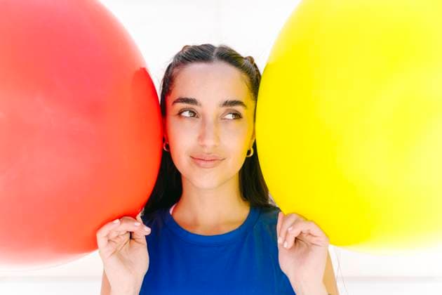 Creative Highlight Symbolbilder Portrait of smiling woman in blue shirt with red and yellow balloons model released, Symbolfoto, JCZF01665
