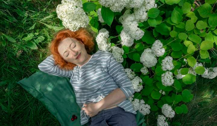 Creative Highlight Symbolbilder Red-haired woman resting with eyes closed on grass by white hydrangea model released, Symbolfoto, MBLF00947