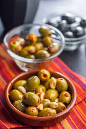 Tapas. Aromatisierte eingelegte Oliven in einer Schale auf einer Serviette. Tapas. Flavored pickled olives in bowl on a kitchen napkin. (License=RF) Copyright: xZoonar.com JirixHERAx 23787900