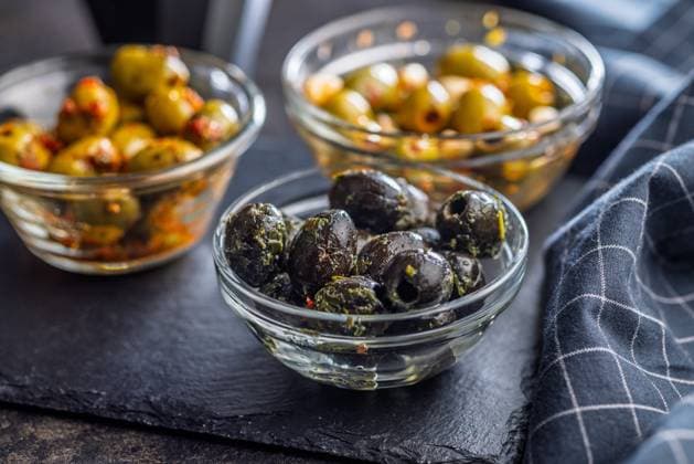 Tapas. Aromatisierte eingelegte Oliven in einer Schale auf einem schwarzen Tisch. Tapas. Flavored pickled olives in bowl on a black table. (License=RF) Copyright: xZoonar.com JirixHERAx 23787935