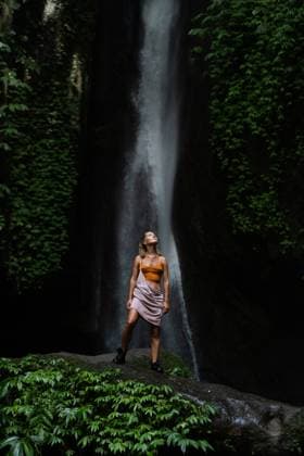 Creative Highlights Symbolbilder Woman standing by waterfall in lush jungle, outdoor adventure Ubud, Bali, Indonesia CR_YUKI250725-1794969-01 ,model released, Symbolfoto