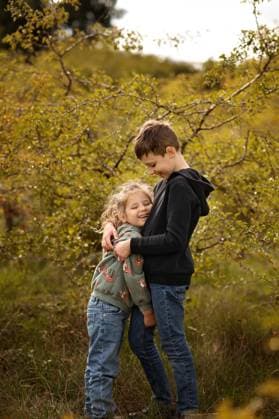 Creative Highlight Symbolbilder Siblings hugging and laughing in autumn forest. Corby, England, United Kingdom R_JNDO250725-1790702-01 ,model released, Symbolfoto