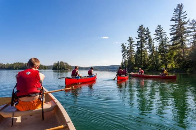 A group of teen boys paddling red canoes on a Canadian lake Temagami, Ontario, Canada R_VAWG250724-1795184-01 EDITORIAL USE ONLY