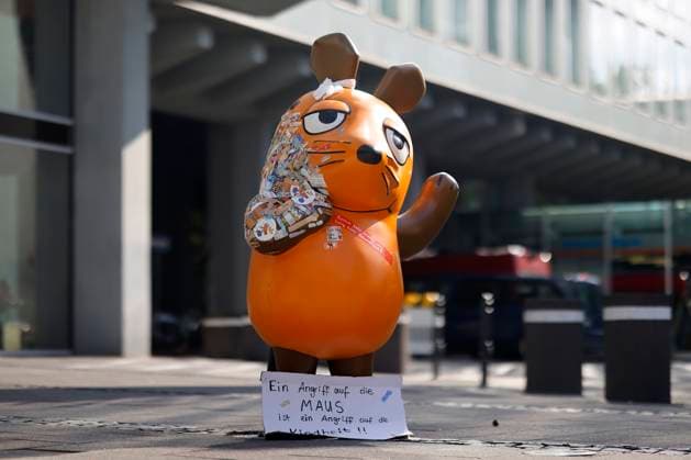 Nach dem Feuer-Anschlag auf die Mausfigur aus dem bekannten TV-Format Die Sendung mit der Maus vor dem WDR kleben viele Passanten aus Solidarität Sticker als Trostpflaster auf die angebrannte Stelle. Unbekannte hatten die Statue in der Nacht auf Samstag in Brand gesteckt. Auf einem Schild zu ihren Füßen steht: Ein Angriff auf die Maus ist ein Angriff auf die Kindheit . Köln, 30.07.2025 NRW Deutschland *** After the fire attack on the mouse statue from the well-known TV format Die Sendung mit der Maus in front of WDR, many passers-by stuck stickers on the burnt area in solidarity Unknown persons had set fire to the statue on Saturday night A sign at its feet reads An attack on the mouse is an attack on childhood Cologne, 30 07 2025 NR Copyright: xChristophxHardtx