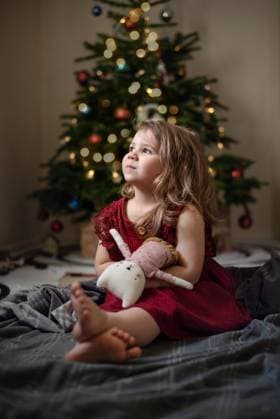 Creative Highlights Symbolbilder A little girl with soft toy sitting front of a Christmas tree, Corby, England, United Kingdom CR_JNDO2507302B-1795590-01 ,model released, Symbolfoto