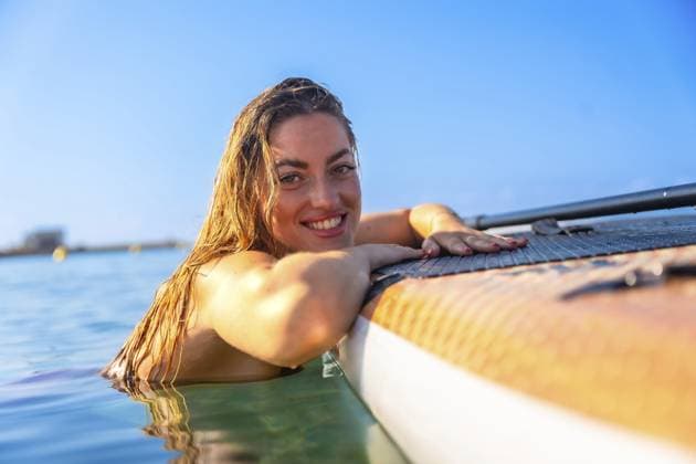 Creative Highlights Symbolbilder Fröhliche Frau, die sich auf einem Paddelbrett im klaren blauen Wasser entspannt und die Freude am Sommer und am Abenteuer im Freien genießt Cheerful woman relaxing on a paddleboard in clear blue water, embracing the joy of summer and outdoor adventure Copyright: imageBROKER UnaixHuizi ibxuhu14482468.jpg ,model released, Symbolfoto ,property released