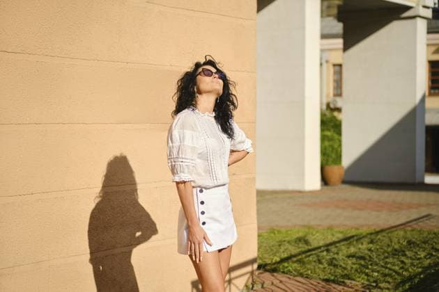 Eine Frau steht spielerisch vor einer braunen Wand in einer hellen Umgebung im Freien und genießt die warme Sonne. Sie trägt eine weiße Bluse und einen Minirock und blickt in die Sonne A woman stands playfully against a tan wall in a bright outdoor environment, enjoying the warm sun. She wears a white blouse and mini skirt and facing the sun Copyright: imageBROKER AlekseixIsachenko ibxfbm14592898.jpg ,model released, Symbolfoto ,property released