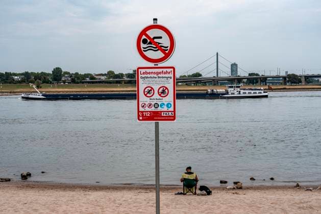 Erster Tag des Badeverbots im Rhein in Düsseldorf, nach 5 Todesfällen im Rhein, innerhalb von 12 Tagen nur in Düsseldorf, hier am beliebten Paradiesstrand, südlich der Innenstadt, sind nur wenige Besucher, trotz Temperaturen über 30Â°C, die meisten Leute gehen, wie erlaubt, nur noch bis zum Fussknöchel ins Wasser, doch immer noch gehen Menschen im Fluss schwimmen, auch Kinder, selbst wenn große Frachtschiffe, mit nur gut 30 Metern vom Ufer vorbei fahren, es drohen Bußgelder bis zu 1000â‚¬, Düsseldorf, NRW, Deutschland, Badeverbot Rhein *** First day of the swimming ban in the Rhine in Düsseldorf, after 5 deaths in the Rhine, within 12 days only in Düsseldorf, here at the popular Paradiesstrand, south of the city center, there are o