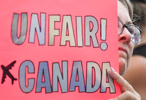 August 17, 2025, Montreal, Pq, Canada: A woman holds a sign alongside Air Canada employees and union members during a protest outside the Air Canada headquarters in Montreal, Sunday, Aug. 17, 2025, after the federal government intervened in the labour dispute between the airline and the union representing its flight attendants, ordering binding arbitration and operations to resume. Montreal Canada  - ZUMAc35_ 20250817_zaf_c35_010 Copyright: xGrahamxHughesx