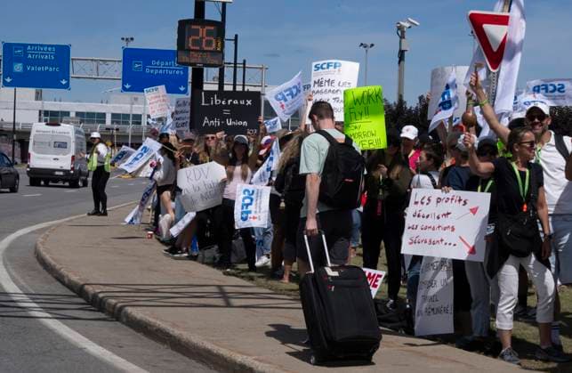 August 18, 2025, Dorval, Pq, CANADA: A traveller walks past Air Canada flight attendants and supporters as they strike outside Montreal-Pierre Elliott Trudeau International Airport in Dorval, Que., on Monday, Aug. 18, 2025. Dorval CANADA  - ZUMAc35_ 20250818_zaf_c35_051 Copyright: xChristinnexMuschix