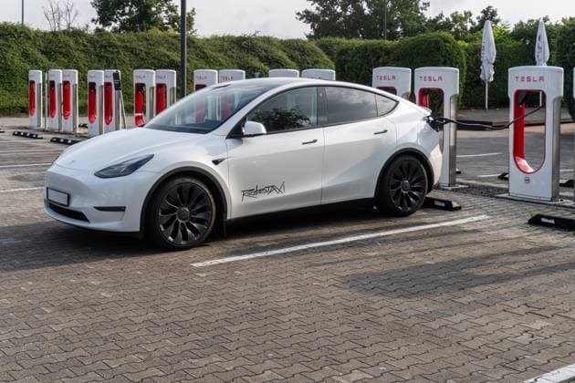 Bavaria, Germany August 19, 2025: PHOTOMONTAGE STICKER, A Tesla with a robotaxi sticker charges at a Supercharger a symbol of autonomous mobility, electromobility, and innovation. The combination of technology and sustainability is shaping the future of driving.