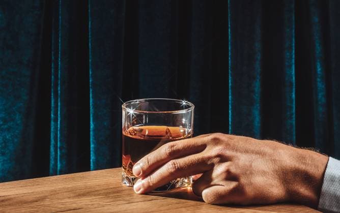 Hand holding whiskey glass on wooden bar table model released, Symbolfoto, AAF00112