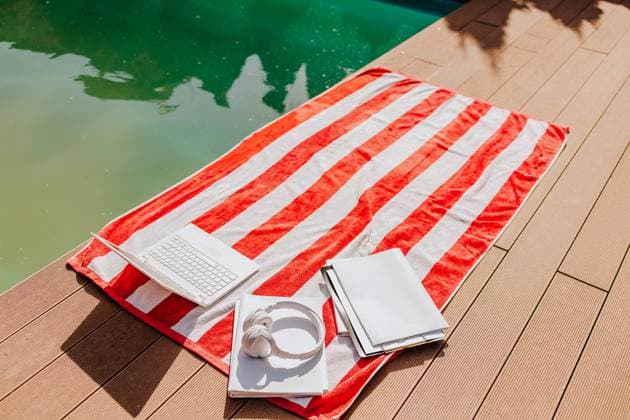 Red striped towel with laptop books and headphones by the pool property released, MDOF02955