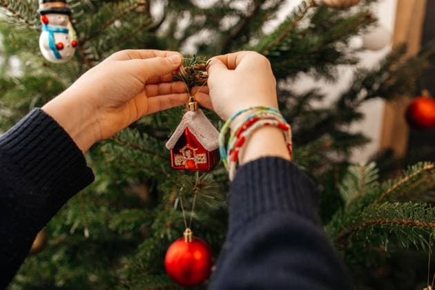 Child decorating Christmas tree with ornament indoors during winter model released, Symbolfoto property released, ELMF01205