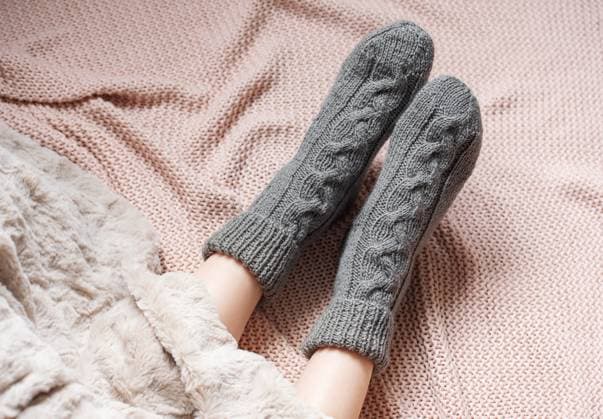 Legs of a young girl in cozy knitted socks. Female legs in warm socks on plaid. Concept of heating season Model Released OlenaRudo_ID31173_1057266_007 Copyright: xx
