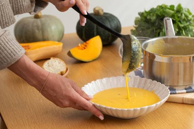 Gemütliche Herbstküche mit Kürbissuppe und frischen Zutaten. Vegane Mahlzeit Autumn pumpkin soup made with fresh ingredients is poured into a bowl on a wooden table. Cozy autumn pumpkin soup. Concept of healthy and vegan meals. (License=RF) Copyright: xZoonar.com ViktoriiaxPopovax 23899611
